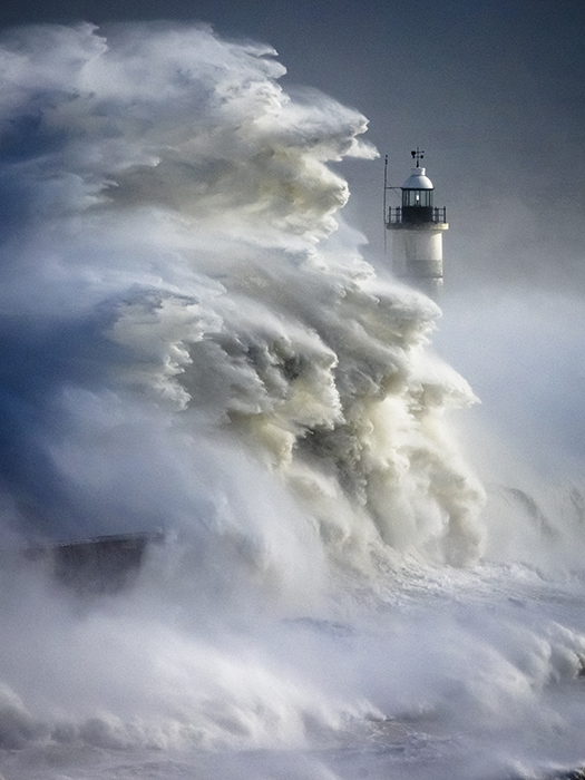 Giant waves from Storm Eunice break over a harbour wall and lighthouse